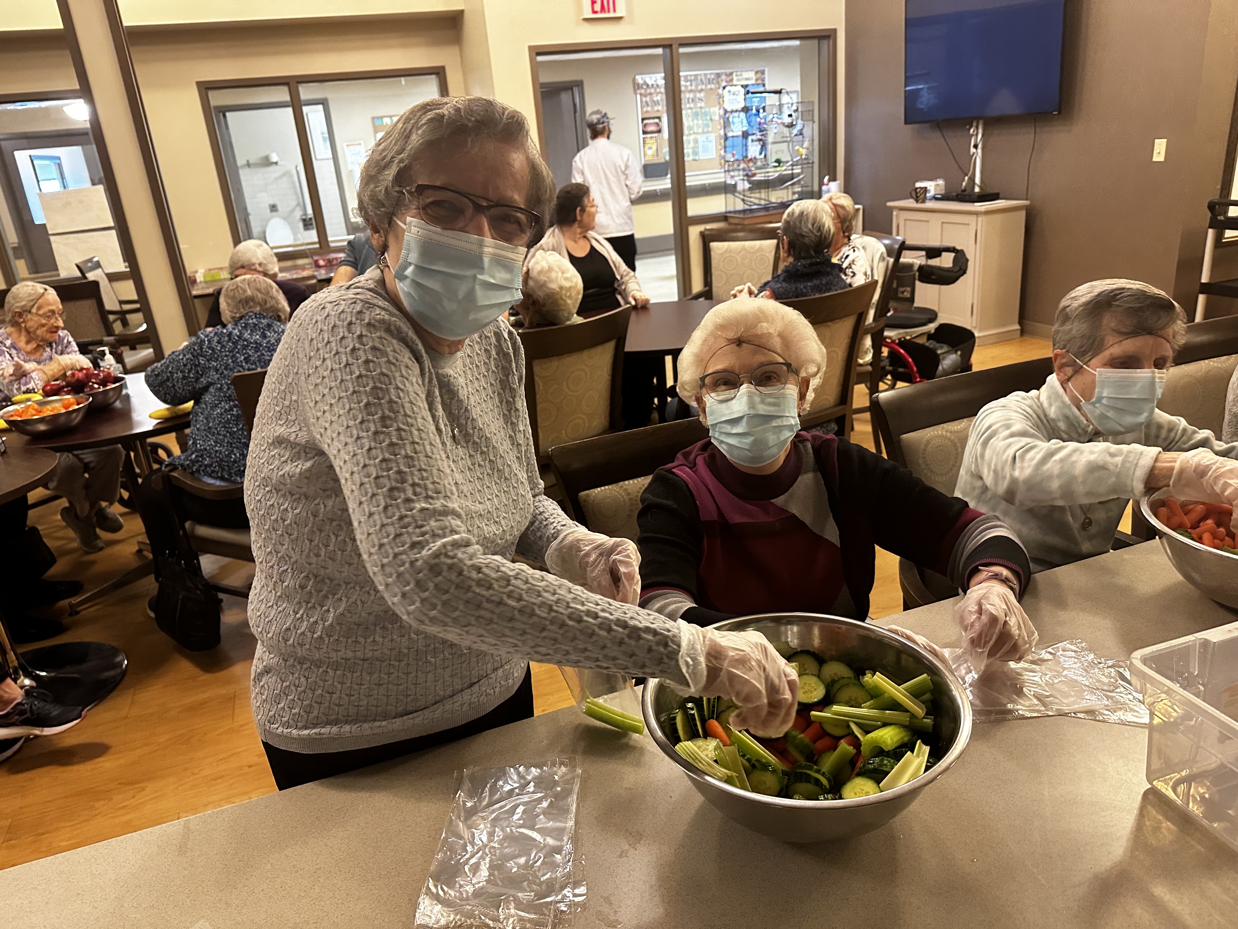 Three residents at a Covenant site mix veggies in a bowl.